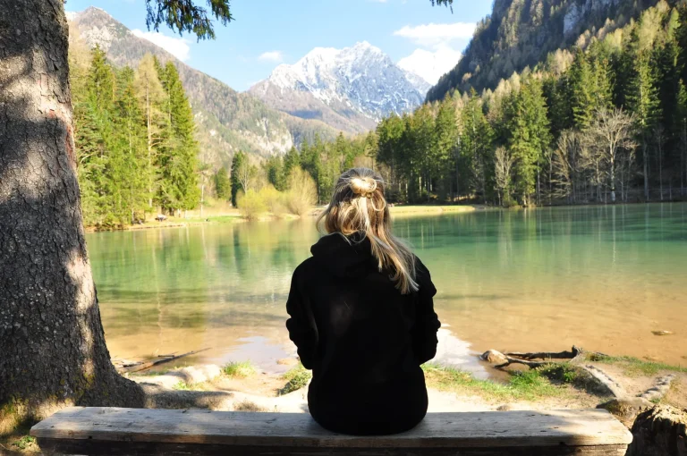 Meisje zittend aan de rand van het Planšarsko jezero in Slovenië. Het Planšaremeer werd door de lokale bevolking gemaakt ter herinnering aan een groter gletsjermeer dat was drooggevallen.