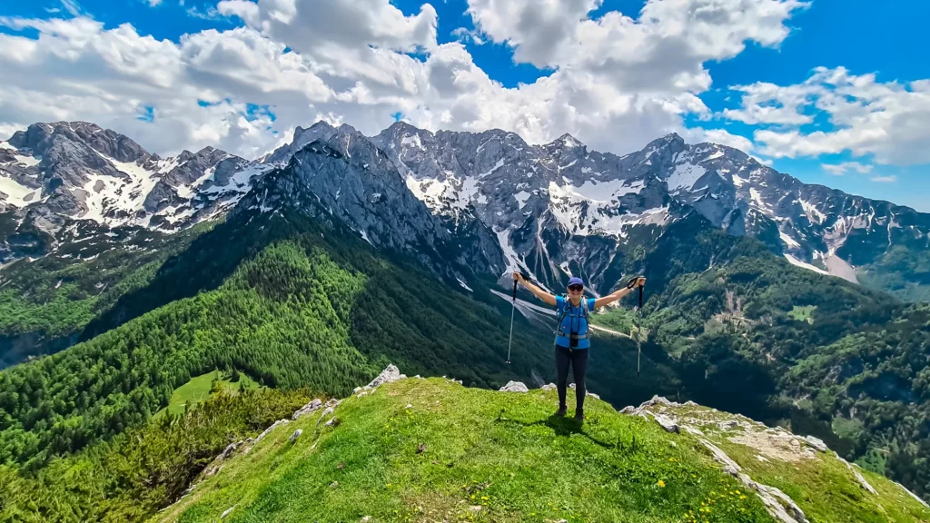 Happy woman spreading her arms out of joy on the summit of Goli Vrh with scenic view on mountains Kamnik Savinja Alps in Carinthia, border Slovenia Austria. Vellacher Kotschna. Mountaineering. Freedom