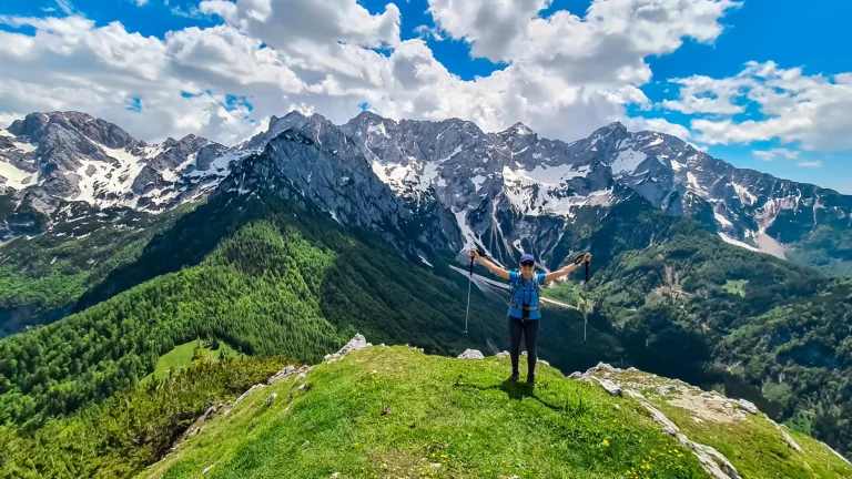 Onnellinen nainen levittää käsiään ilosta Goli Vrh:n huipulla, josta on maisemallinen näkymä Kamnik Savinja Alpeille Kärntenissä, Slovenian ja Itävallan rajalla. Vellacher Kotschna. Vuorikiipeily. Vapaus